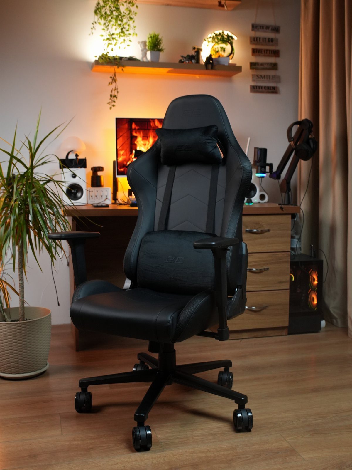 Black ergonomic gaming chair with headrest in a warmly lit home office setting.