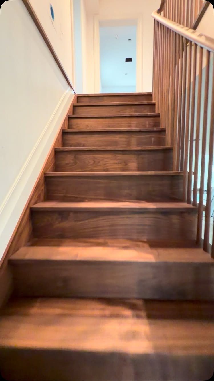 Dark brown wooden stairs with a matching railing leading to a white doorway.