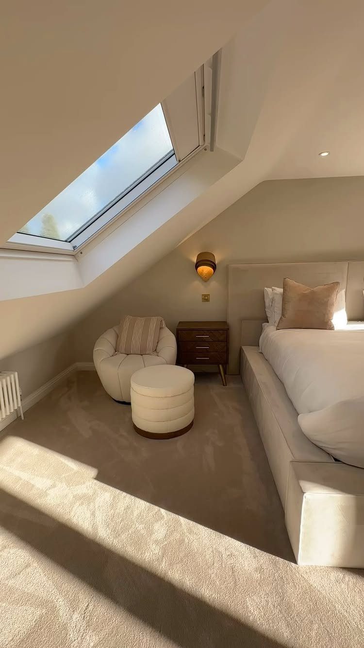Attic bedroom with sloped ceilings, a skylight window, and neutral toned furniture.