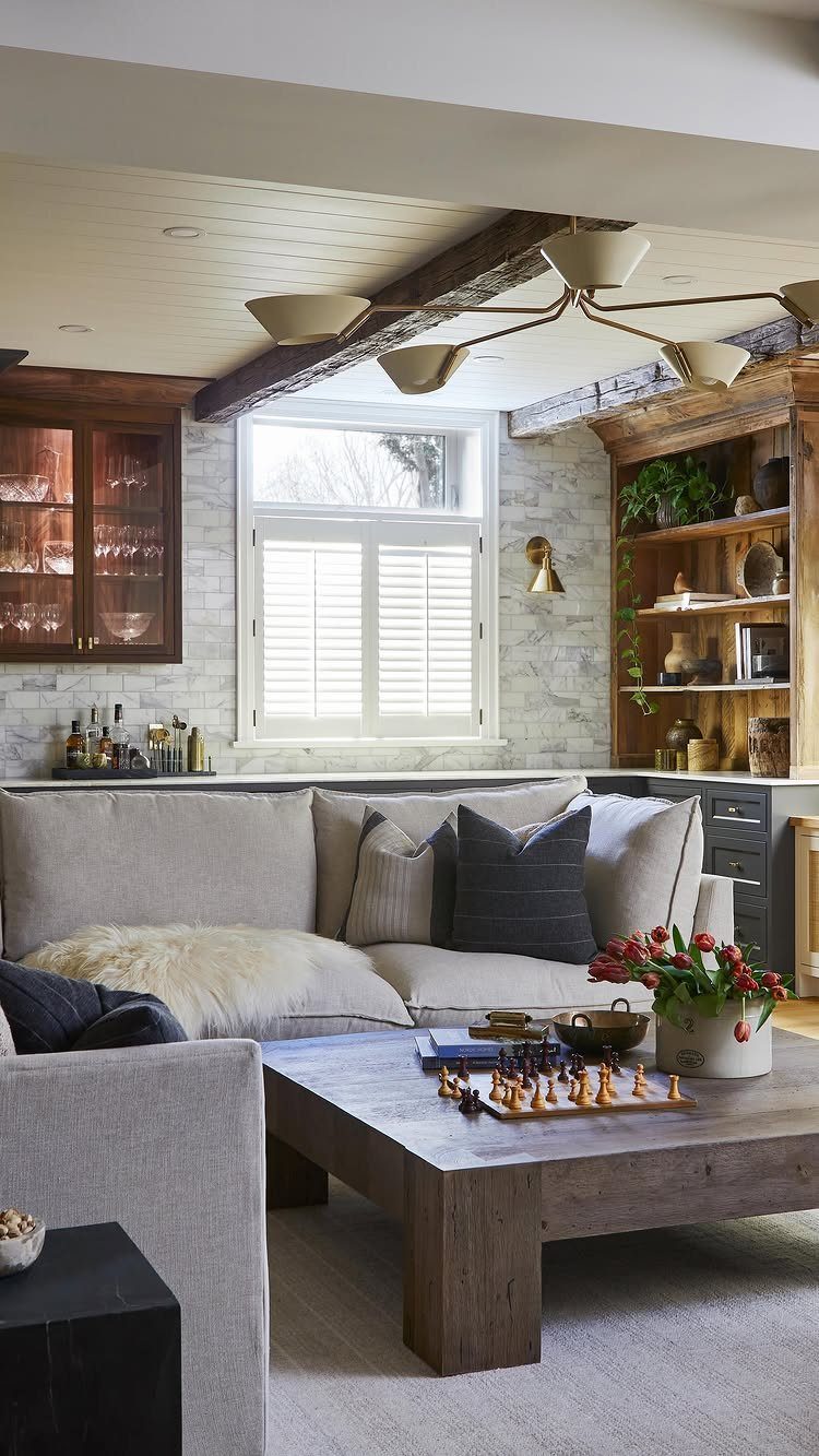 Cozy basement living room with grey sectional, wooden coffee table, and modern ceiling lighting.