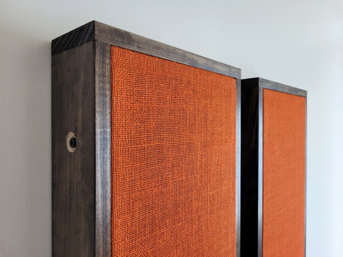 Orange fabric acoustic panels with dark wooden frames on a white wall.