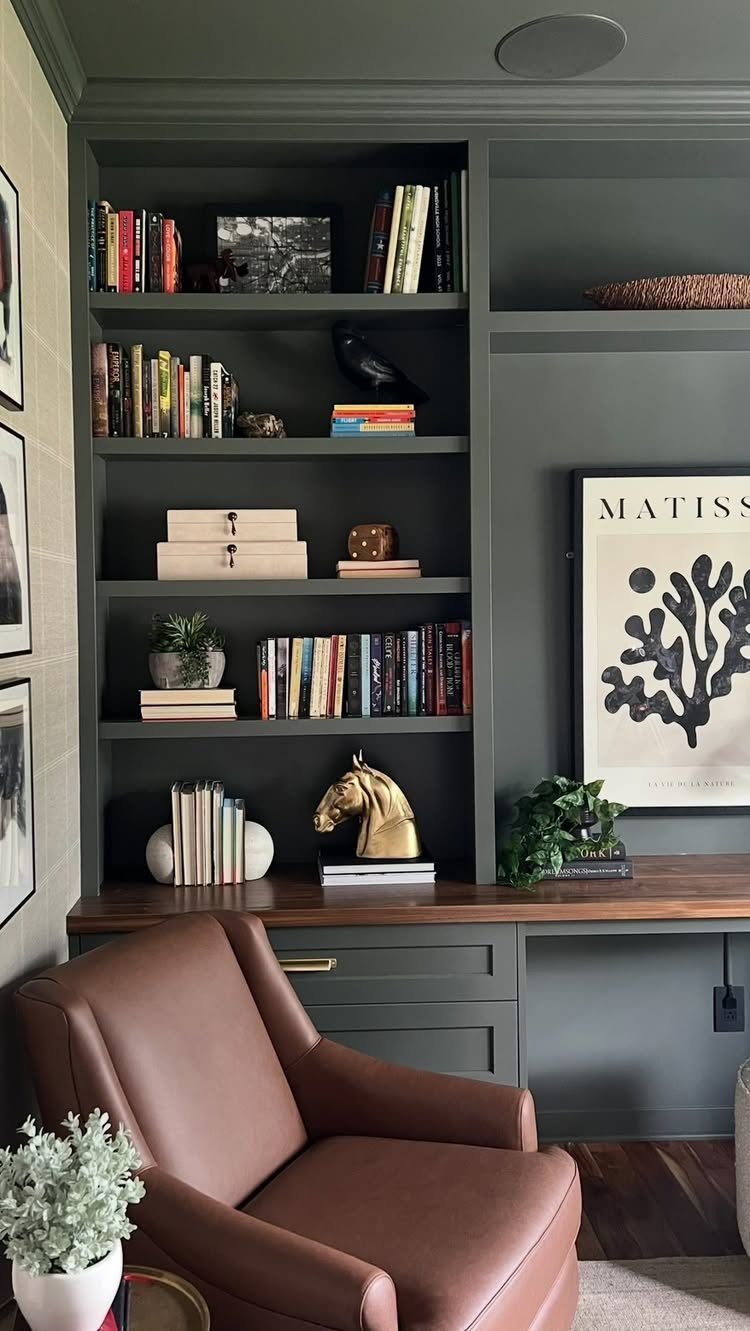 Dark grey built-in bookshelves and a brown leather chair in a home office.