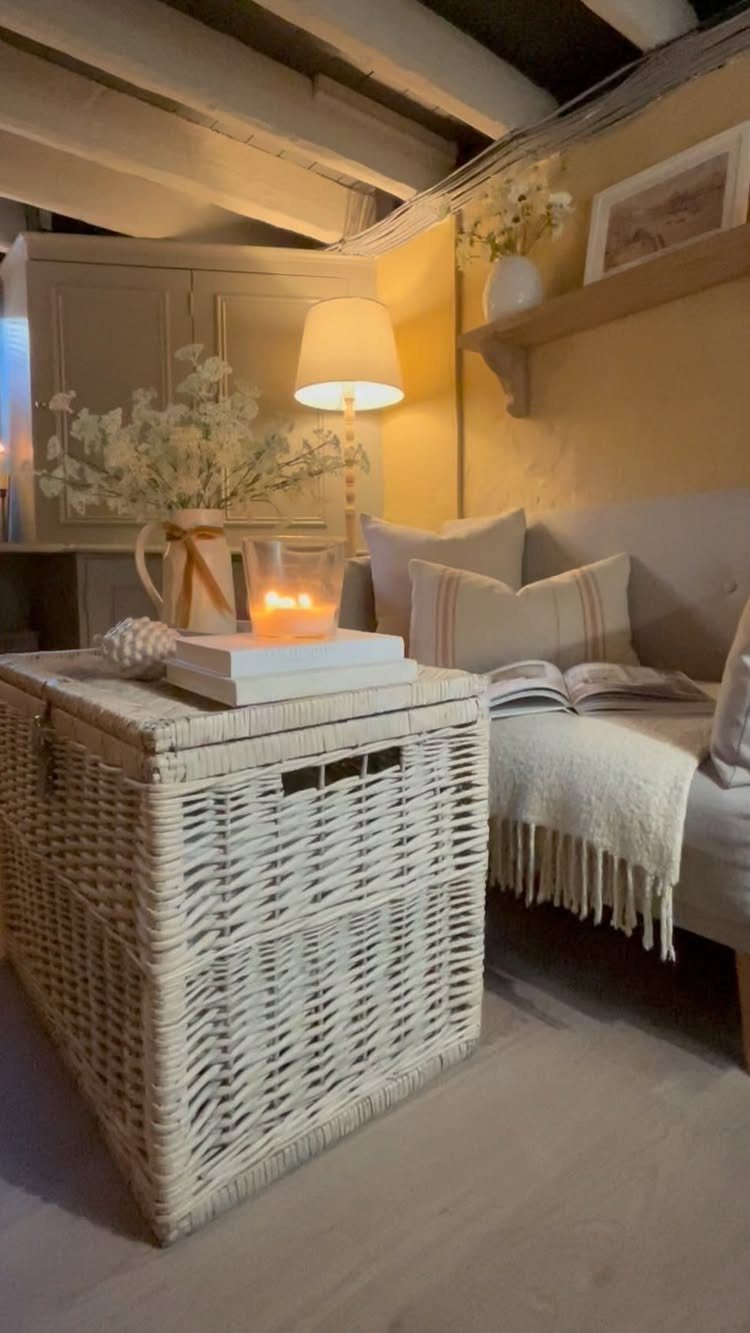 Cozy reading nook with light yellow walls, white ceiling beams, and wicker furniture.