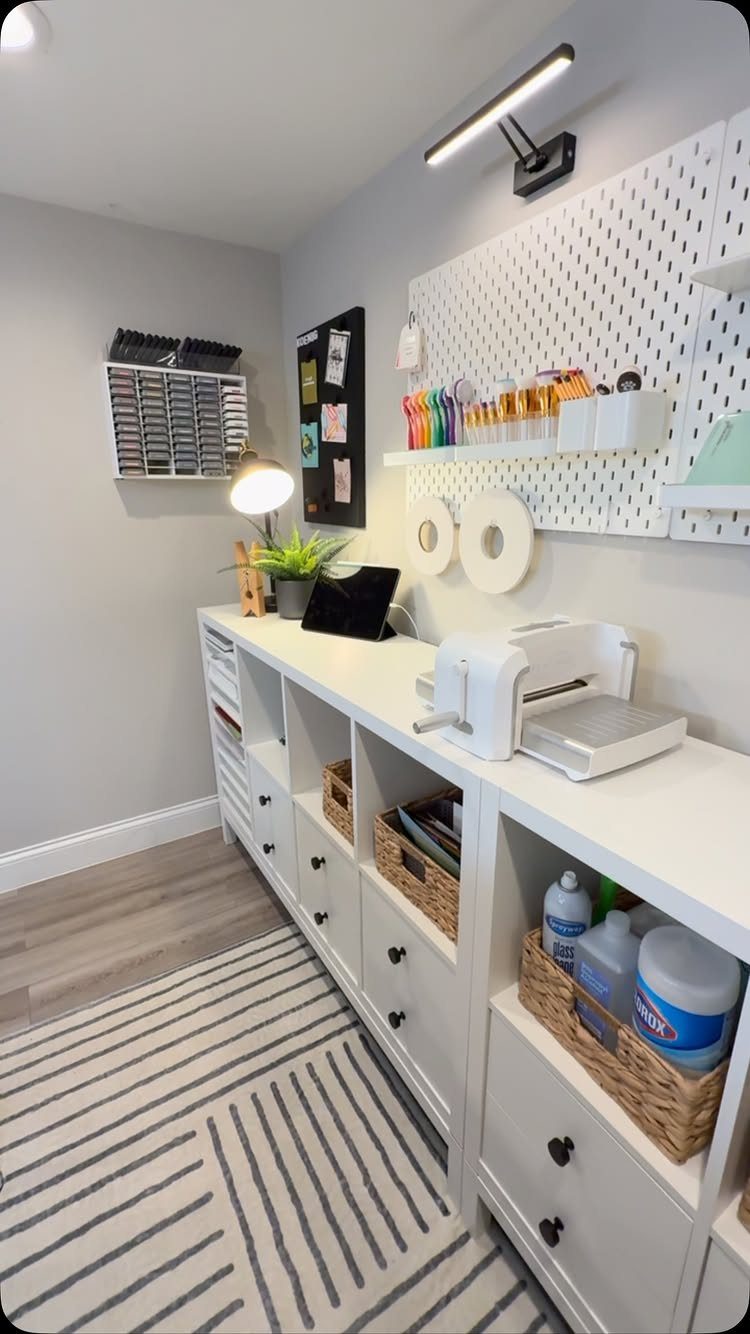 White craft station with a pegboard, paper cutter, and storage baskets against grey walls.