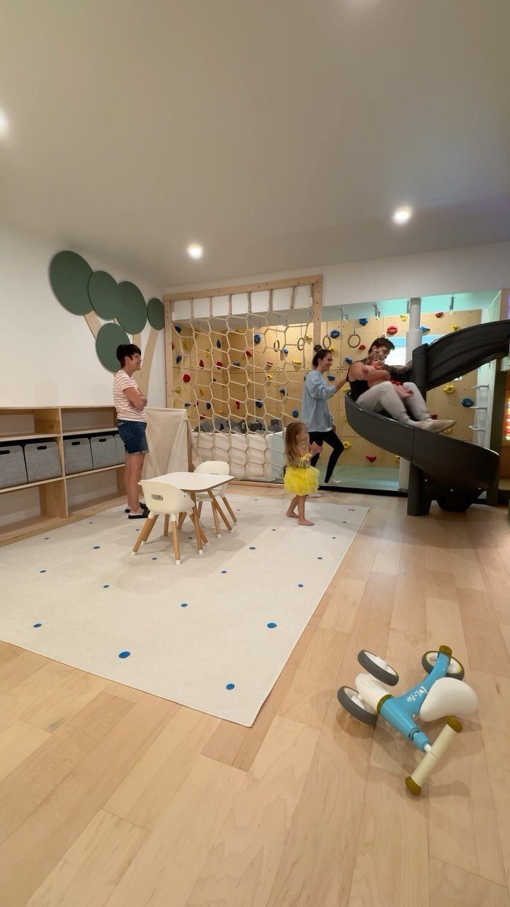 Indoor family play zone with a slide, climbing wall, and children's furniture.