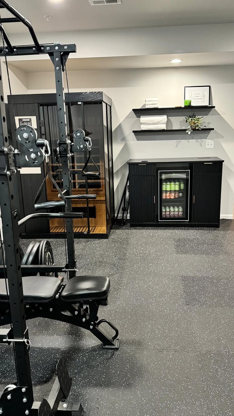 Home gym with a black weight rack, weight bench, and beverage cooler in a basement.