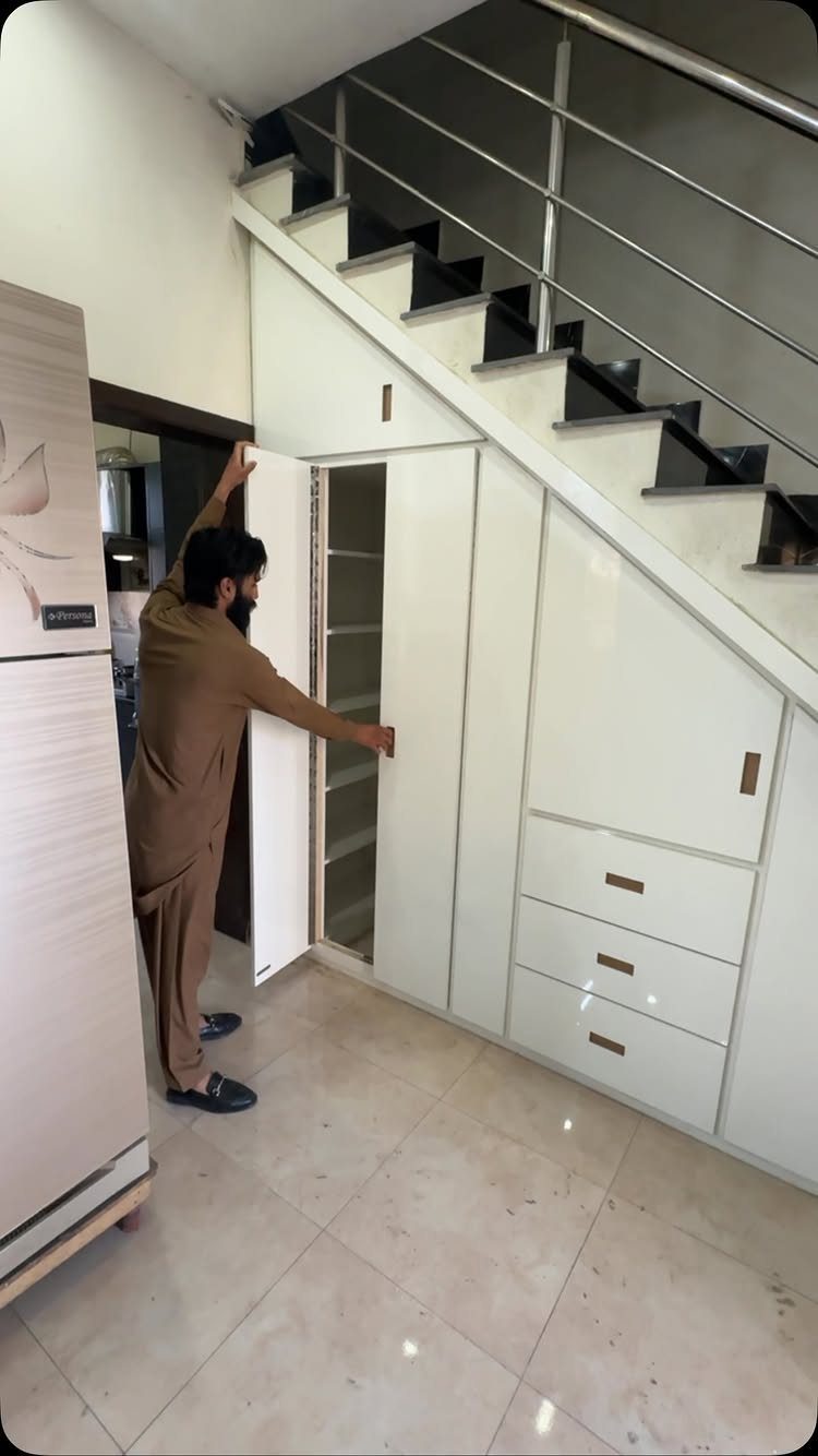 White custom cabinets built under a staircase with a man opening a door.