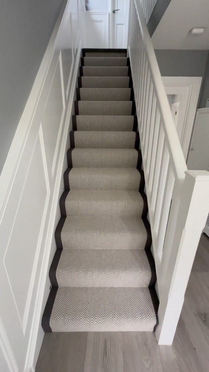 Beige carpet runner with dark brown borders on a white staircase