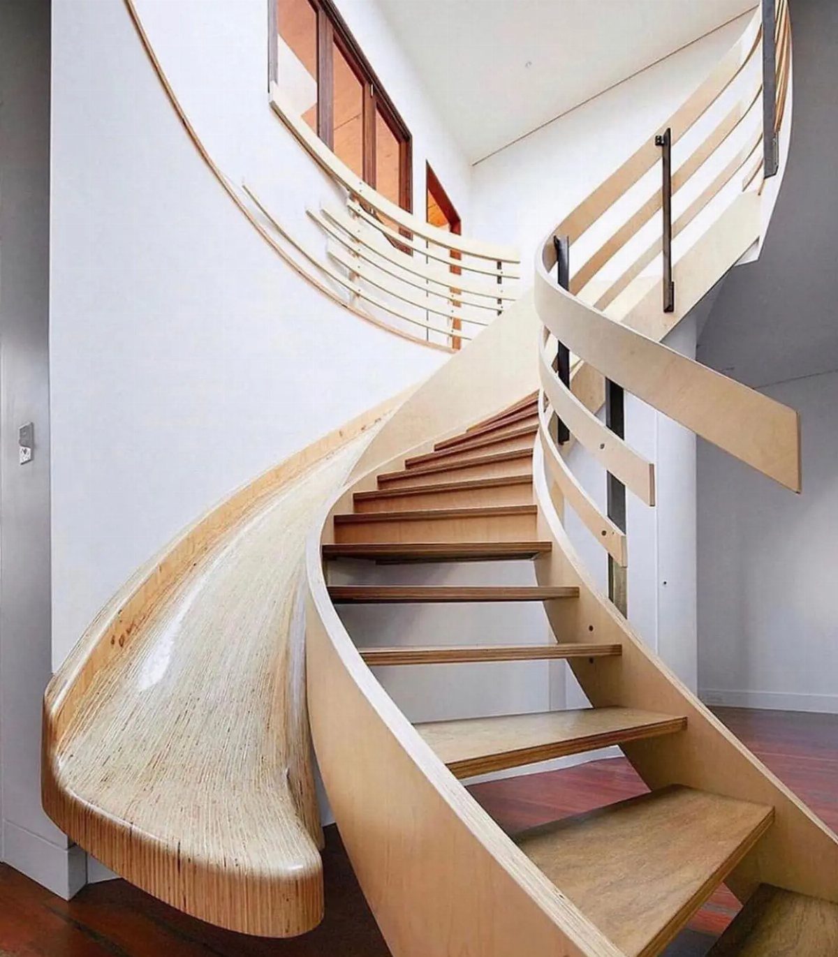 Wooden spiral staircase with an integrated wooden slide curving down to the floor.