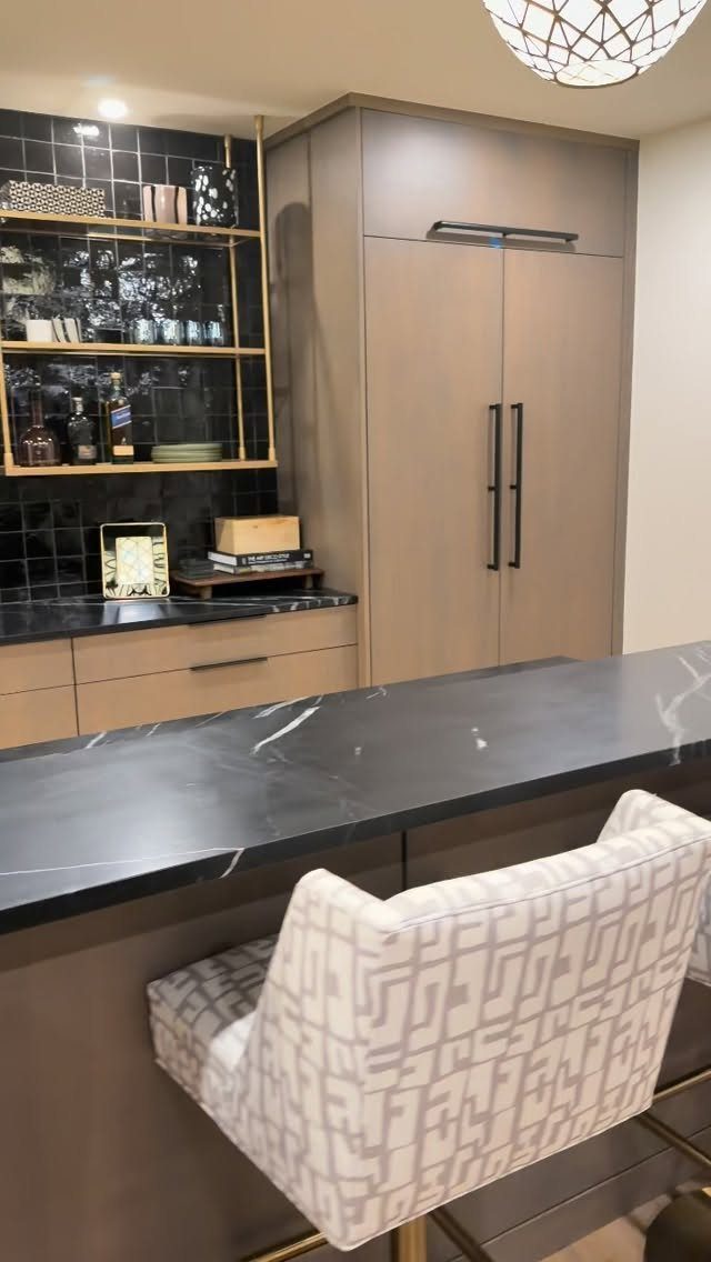 Custom light wood cabinetry and black marble countertop in a modern home bar.