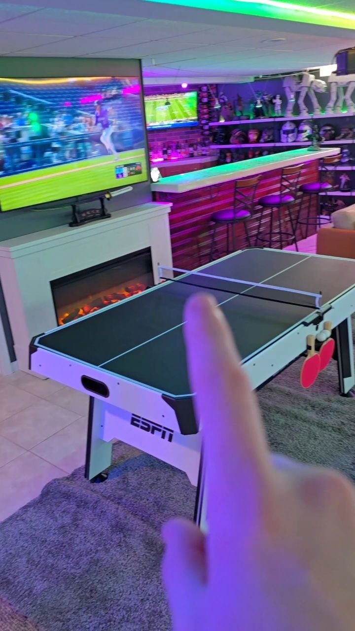 Game room with a ping pong table, large TV, and neon-lit bar area.