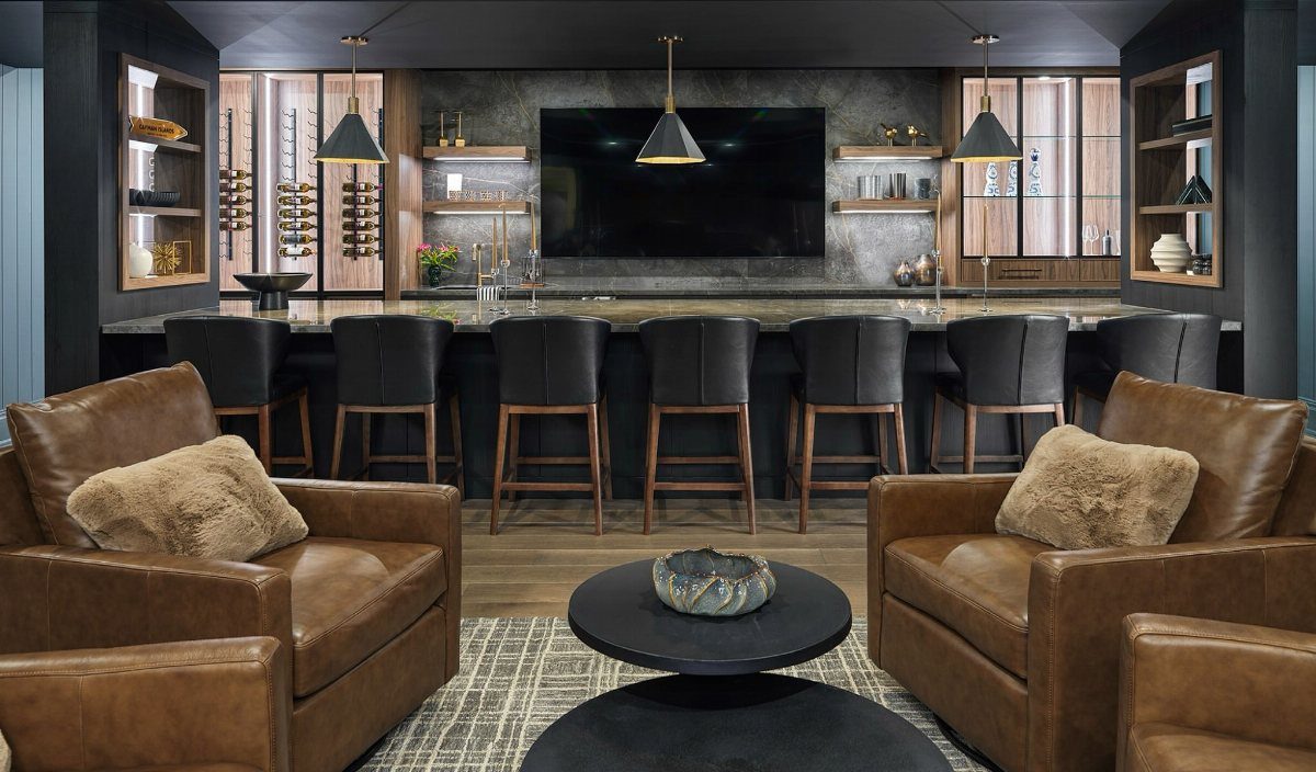 Luxurious dark basement bar with leather chairs, black stools, and integrated wall shelving.