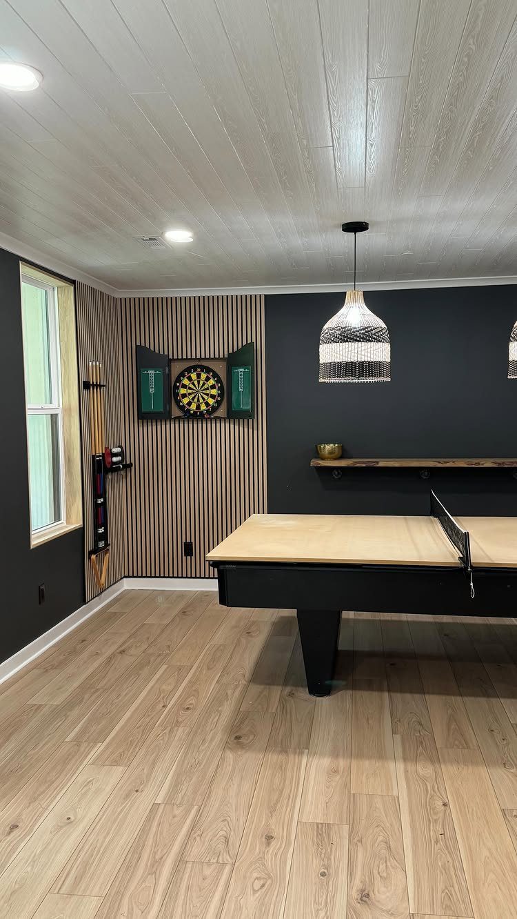 Game room featuring a ping pong table and dartboard on a slatted wood wall.