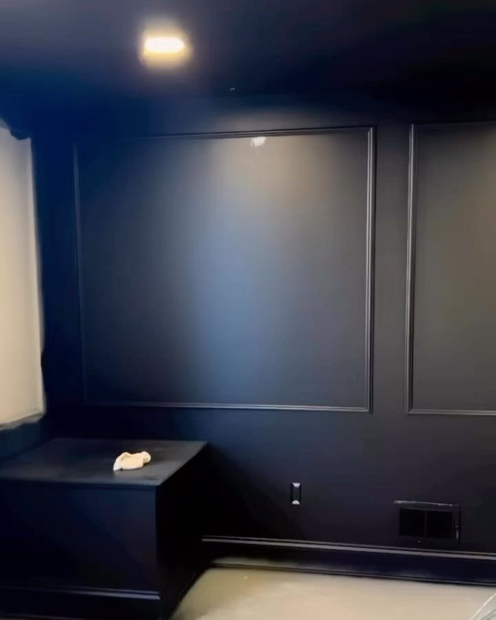 10 Basement Wall Paint Ideas to Refresh Your Space 7 Black painted walls with decorative molding and a black cabinet in a dark room
