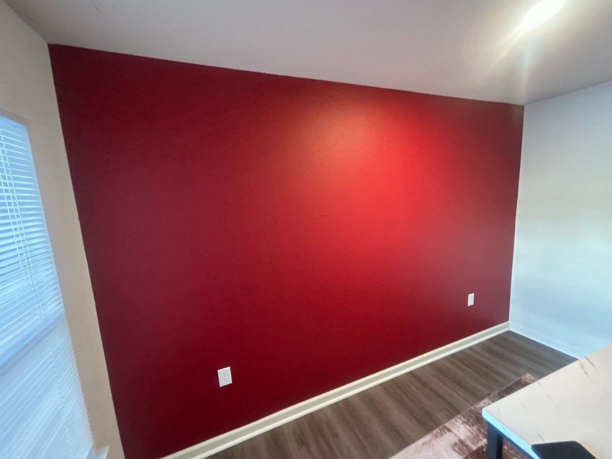 10 Basement Wall Paint Ideas to Refresh Your Space 9 Red accent wall in a room with white trim and dark wood floors.
