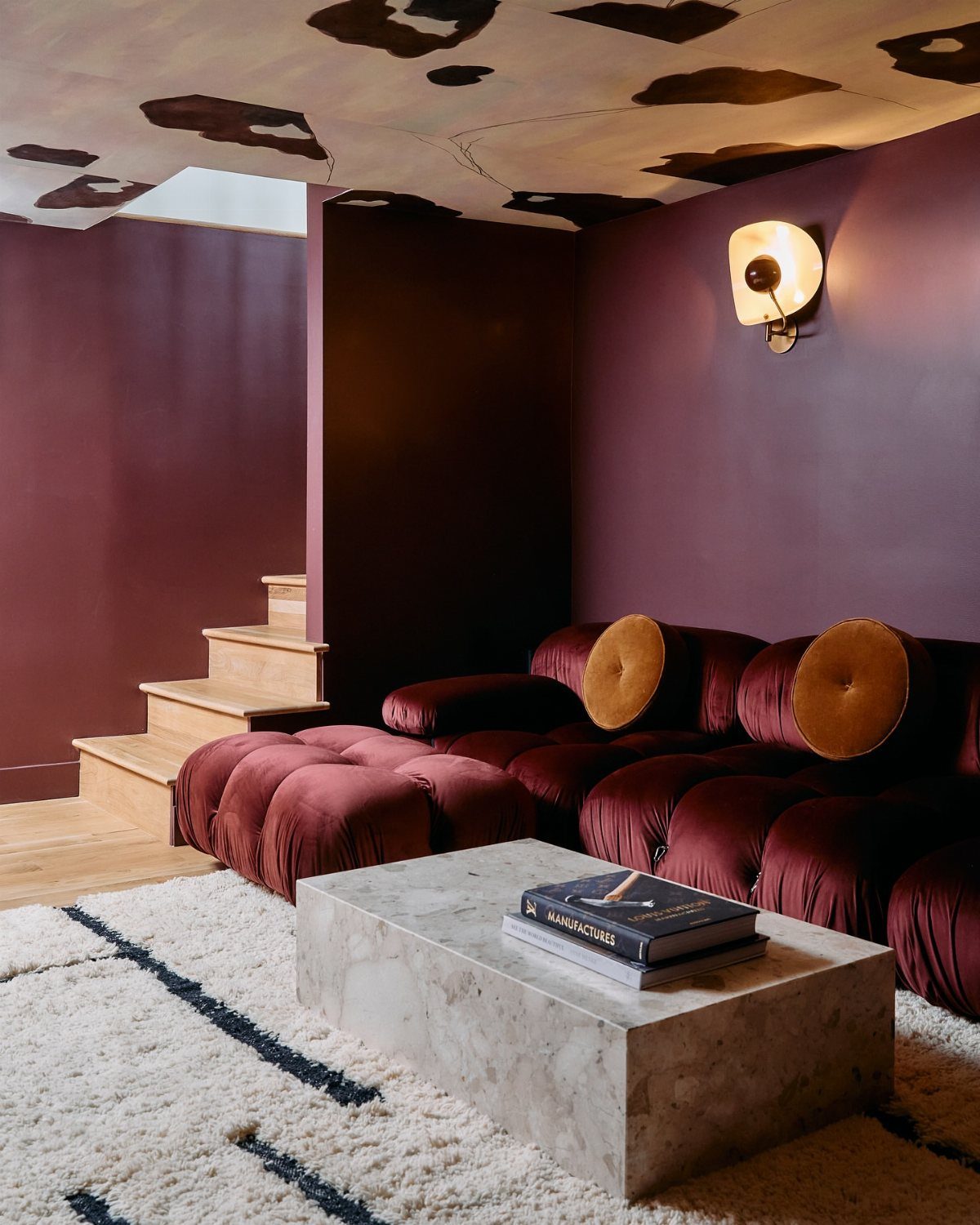 10 Basement Wall Paint Ideas to Refresh Your Space 10 Deep burgundy walls in a living room with a matching velvet sofa and marble table.