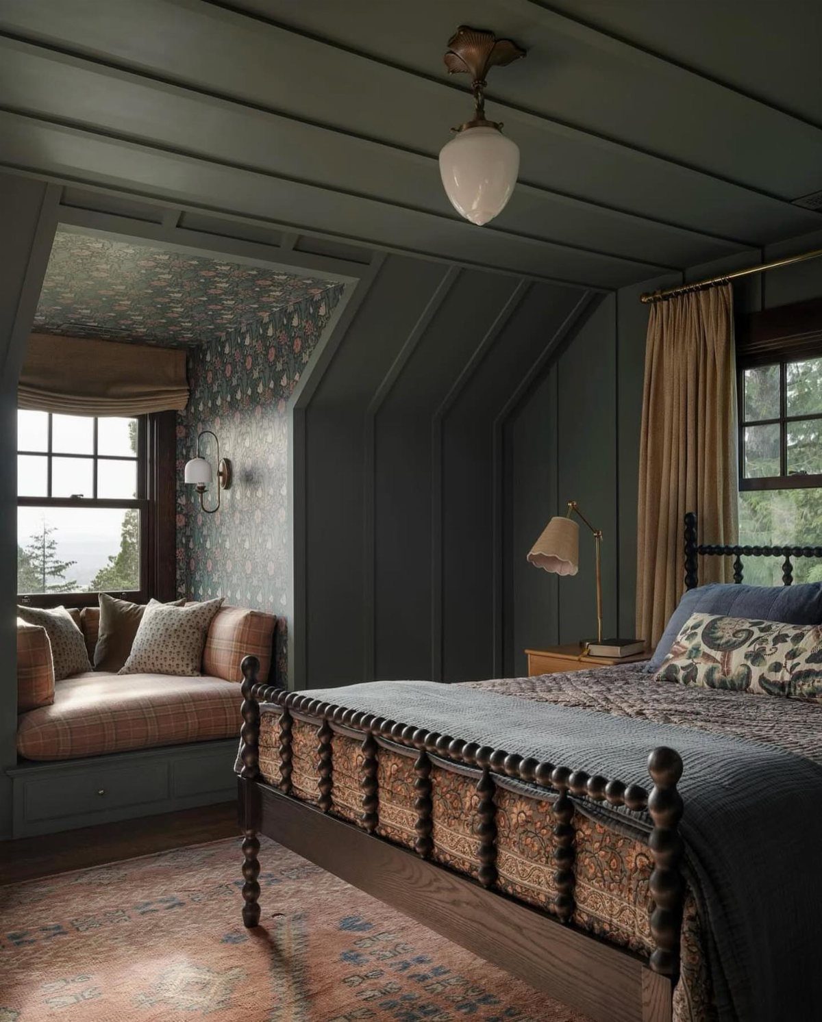 Attic bedroom with blue-grey walls, a wooden spindle bed, and a patterned wallpaper accent wall.