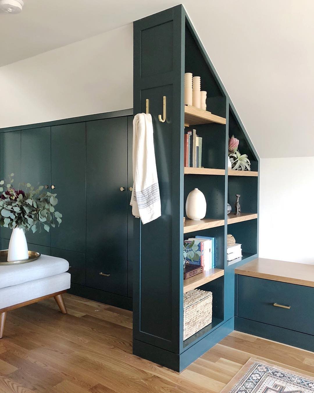 Dark teal built-in wardrobes and shelving units fitted under a sloped attic ceiling.