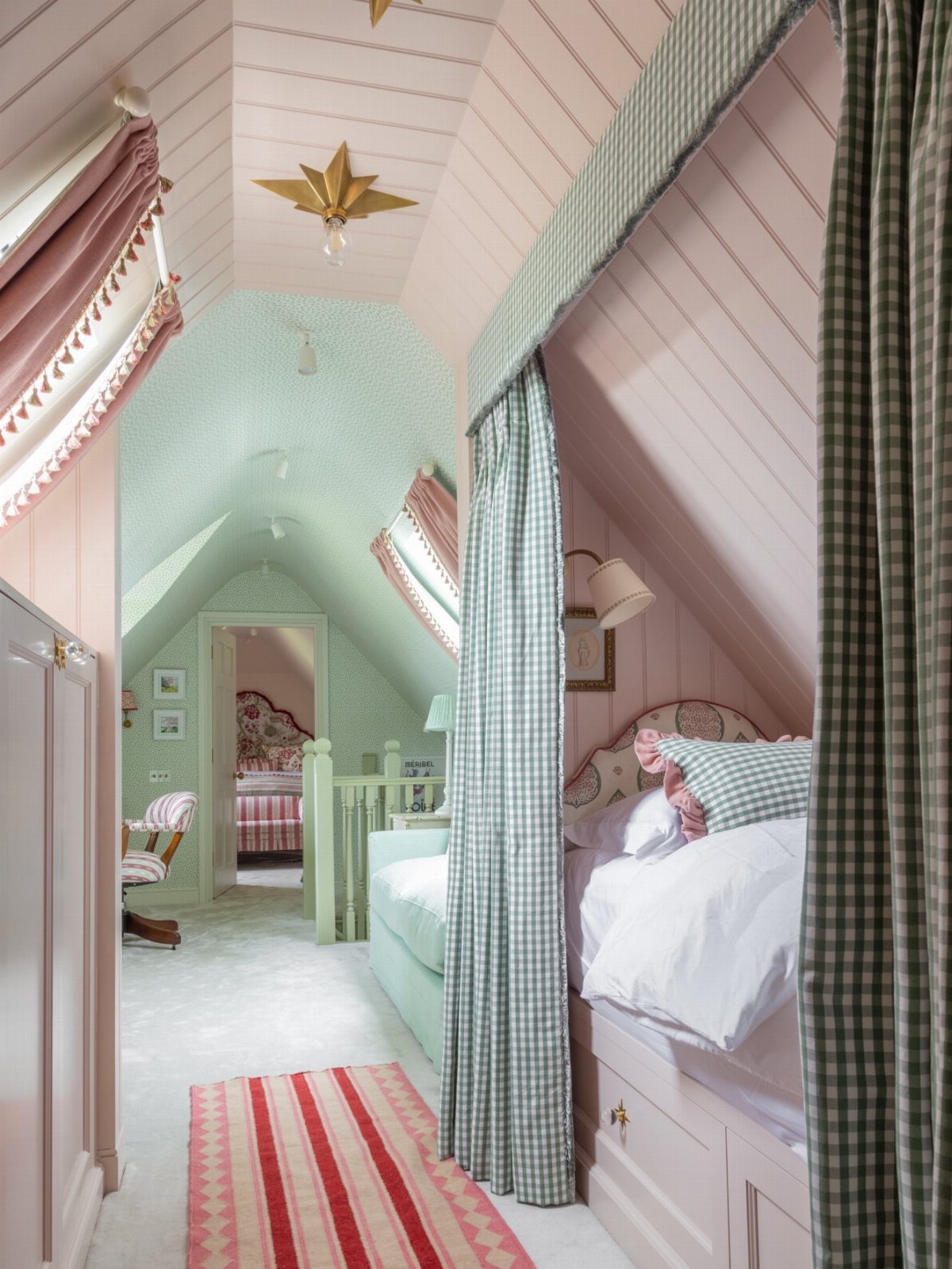 Attic bedroom with a bed in a curtained alcove and sloped pink ceilings.