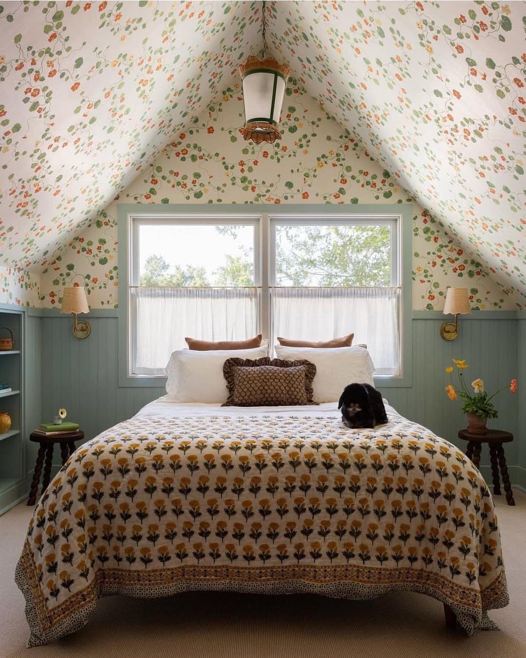 Attic bedroom featuring floral wallpaper on sloped ceilings and a patterned quilt.