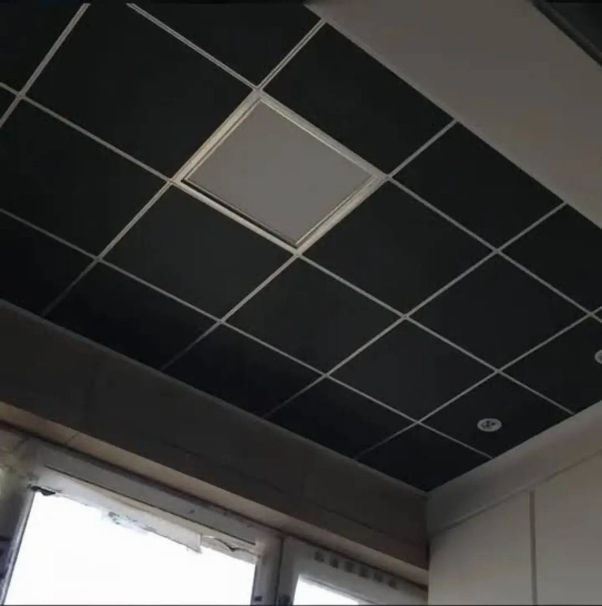 11 Black Ceiling Basement Ideas with Real Impact 2 Black drop ceiling tiles with a white recessed light panel and grid lines.