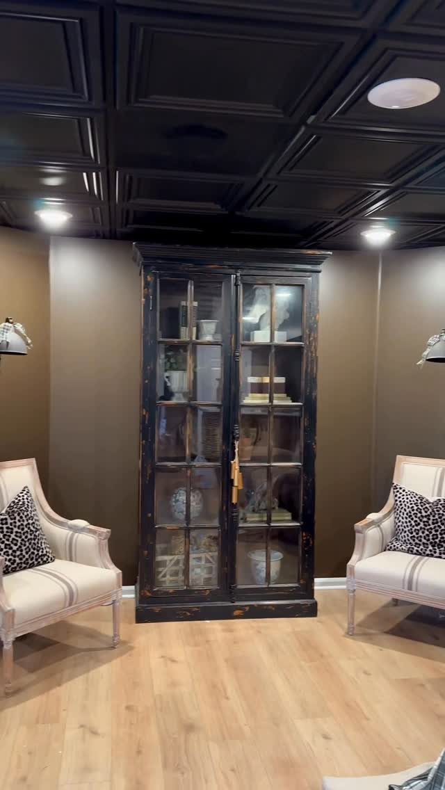 11 Black Ceiling Basement Ideas with Real Impact 6 Black coffered ceiling with recessed lights above a dark wood display cabinet and armchairs.