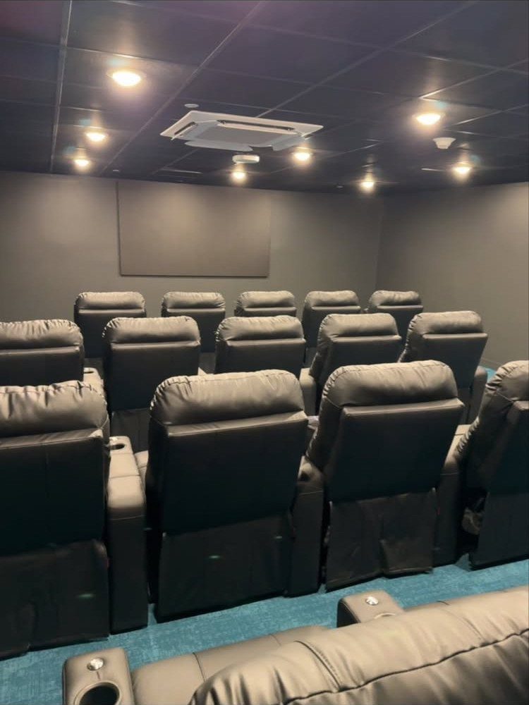Blue carpet in a home media room with black leather reclining cinema seats.
