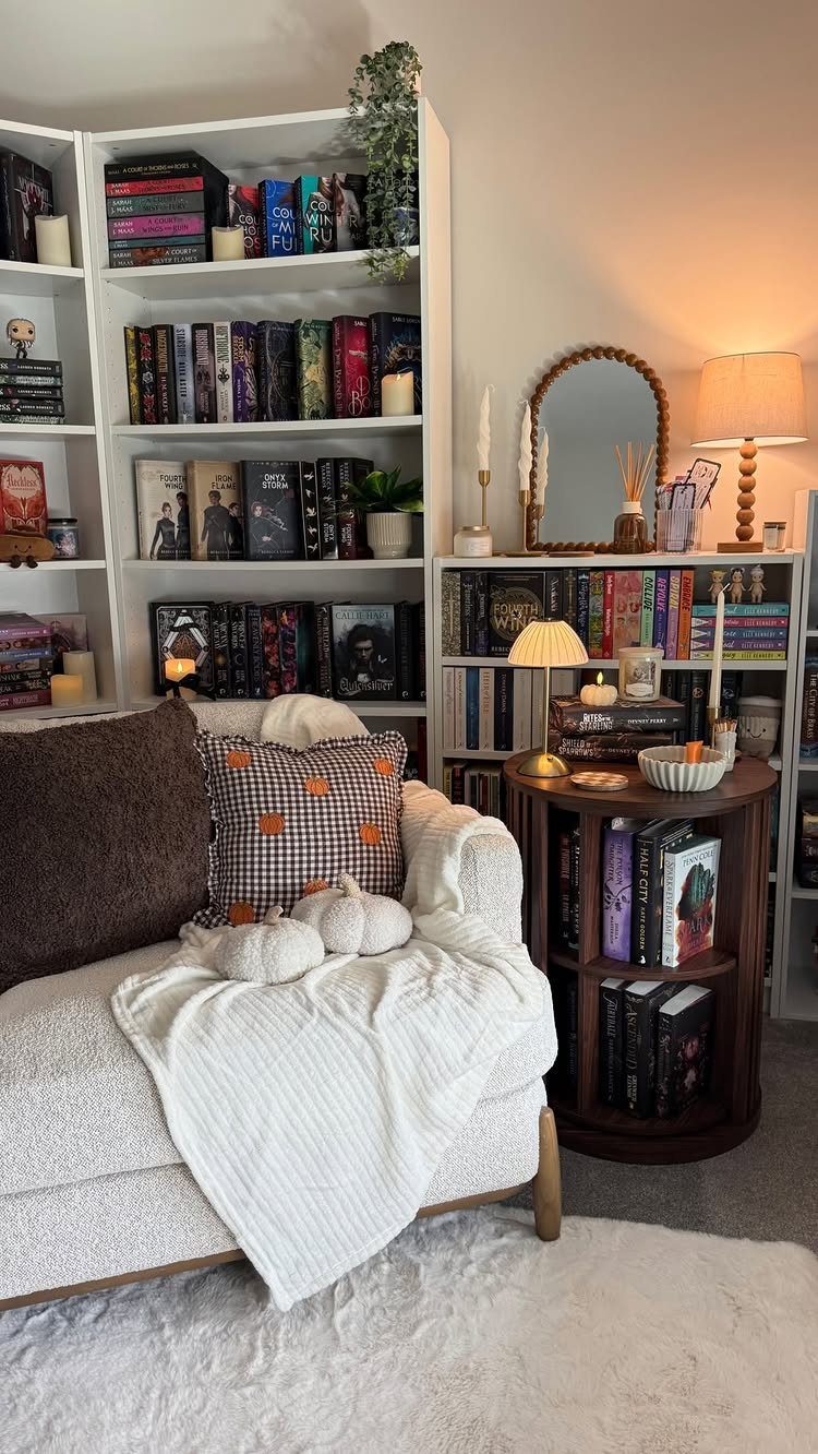 White armchair with cozy blankets and pillows next to bookshelves and warm lighting.