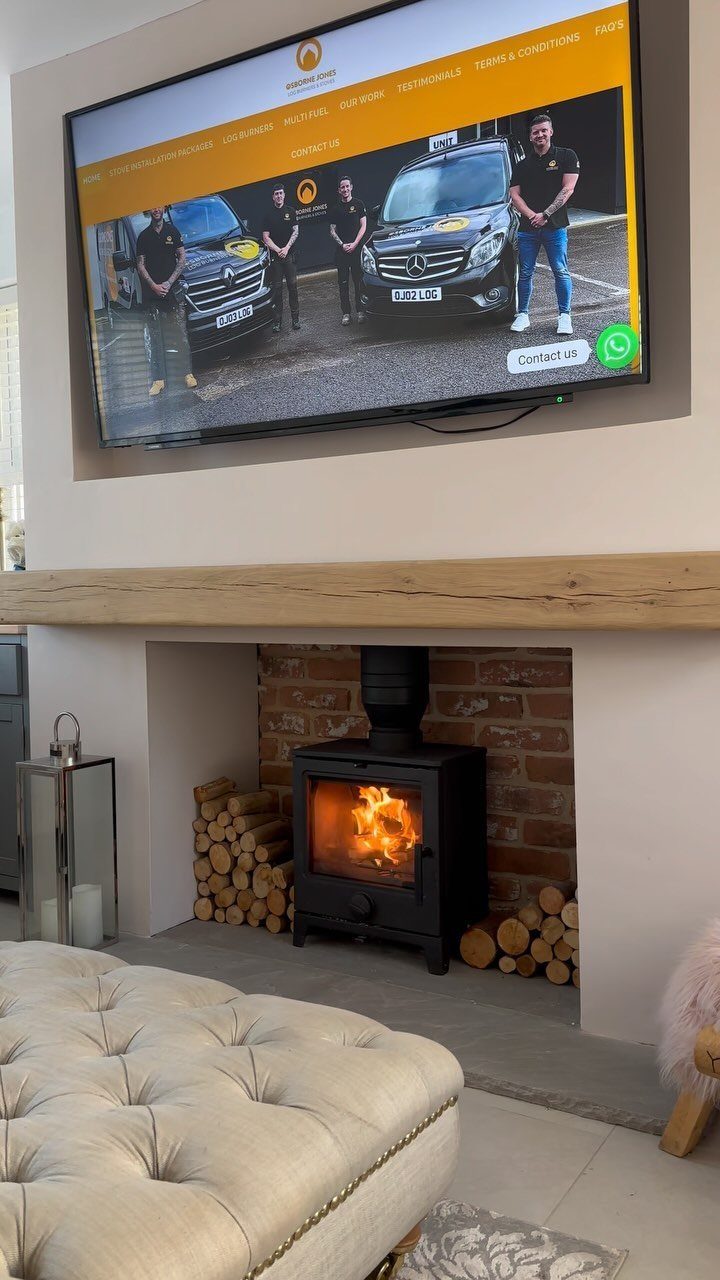 Rustic wooden beam mantel over a brick fireplace with a mounted television above.