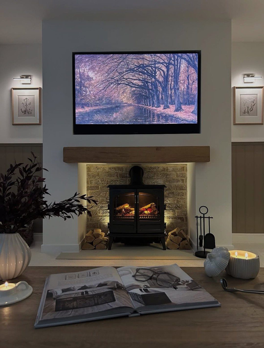 Black wood-burning stove with a wooden mantel and a television mounted above it.
