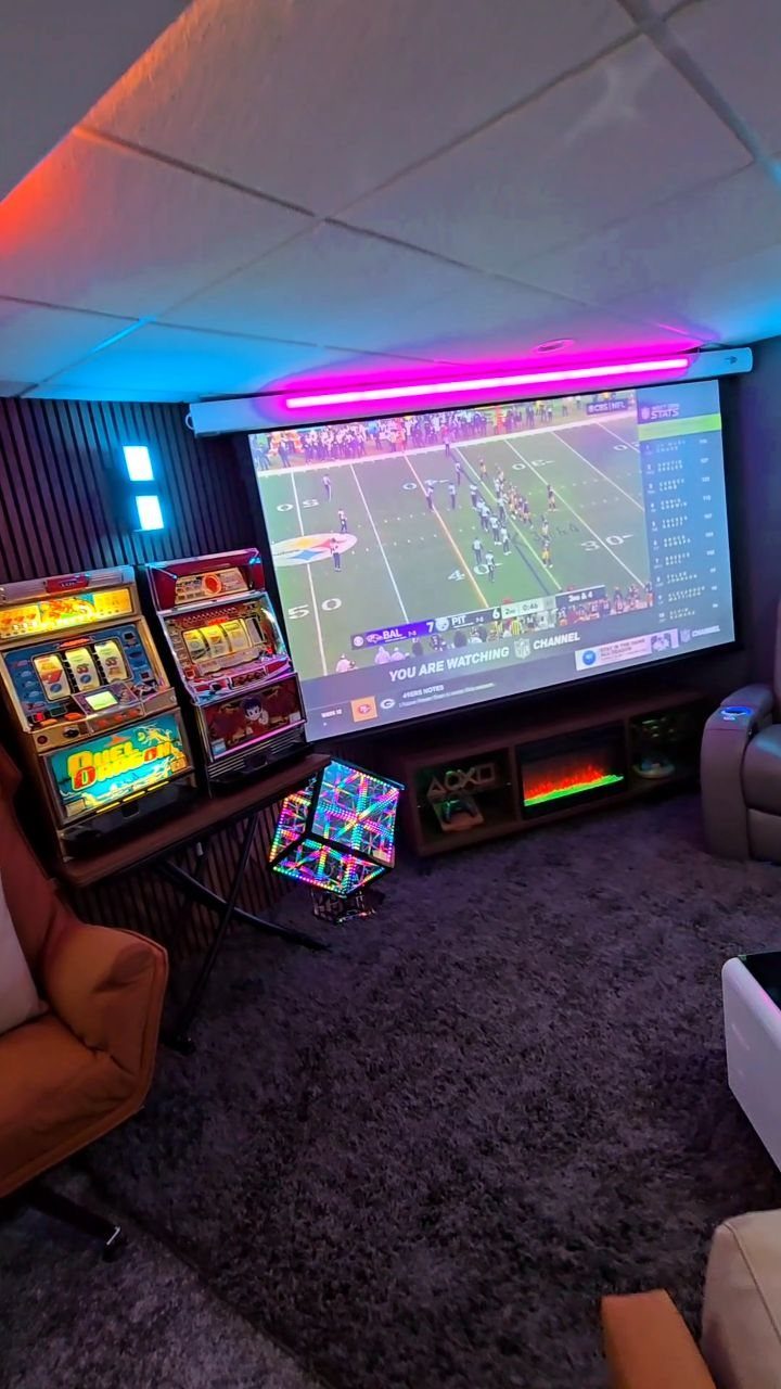 Large projection screen showing football in a game room with slot machines and LED lighting.