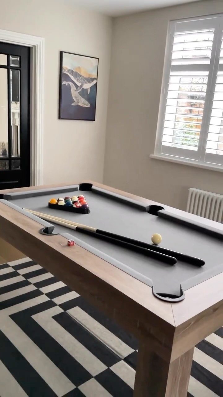 Grey pool table with wooden frame in a minimalist room with geometric rug.