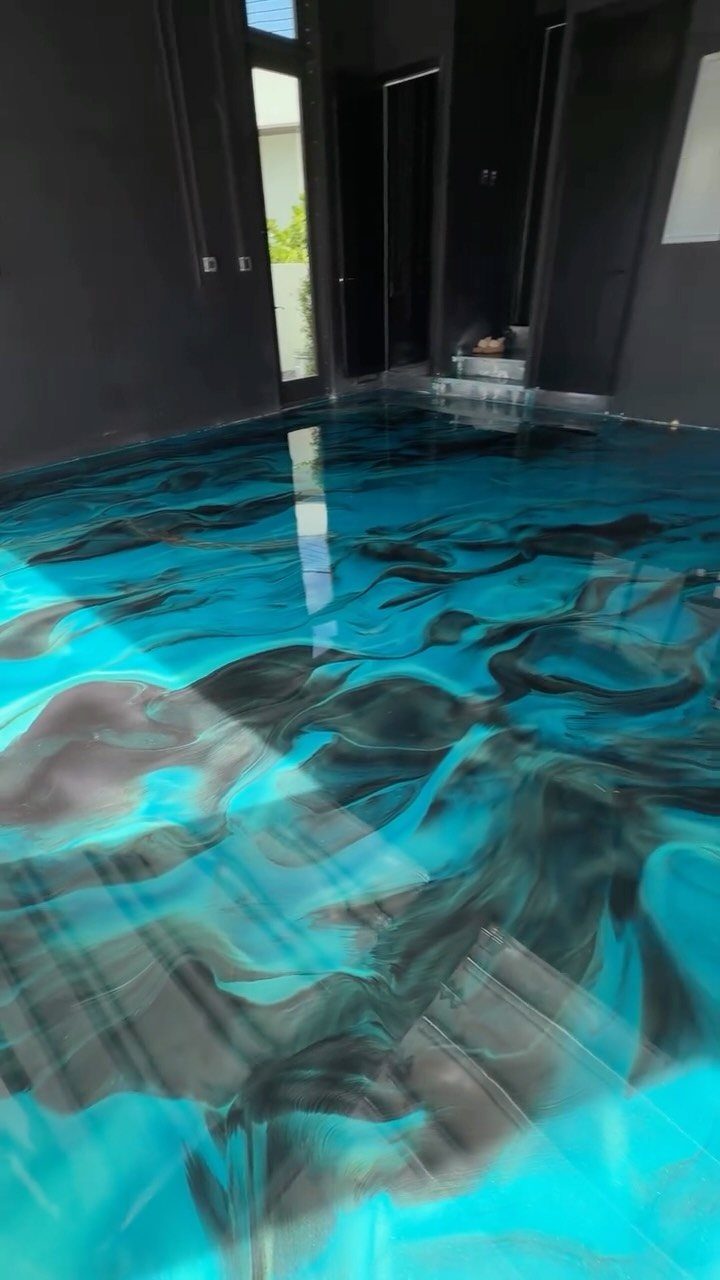 Glossy turquoise and black epoxy floor in a room with dark grey walls.