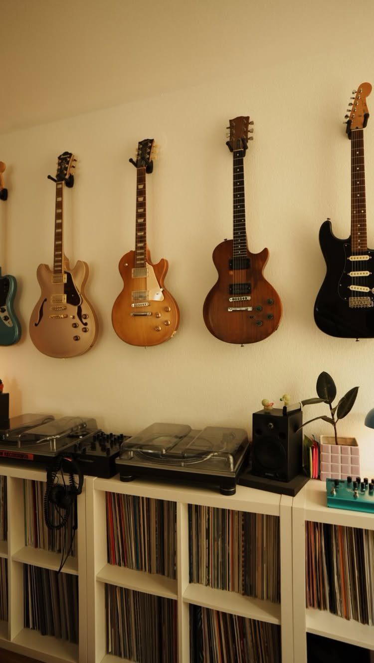 Electric guitars hanging on a white wall above vinyl records and a turntable.