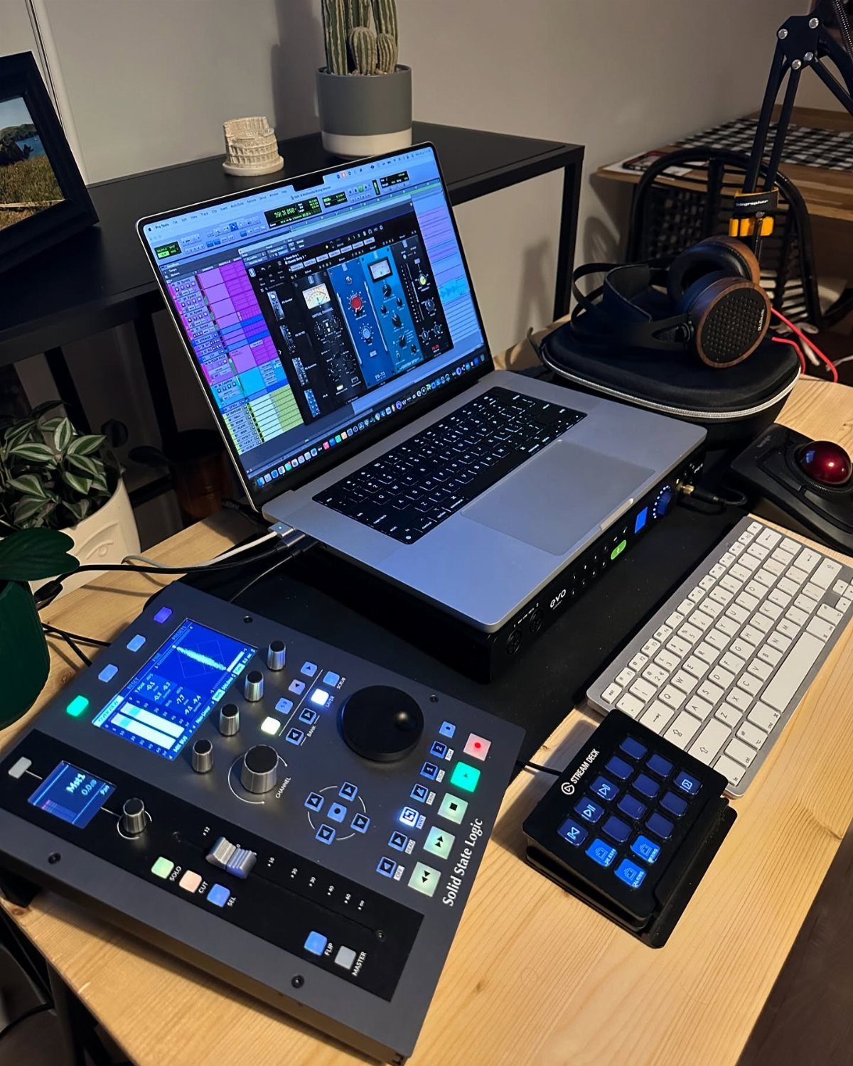 Music production setup with laptop, mixing console, MIDI controller, and headphones on desk
