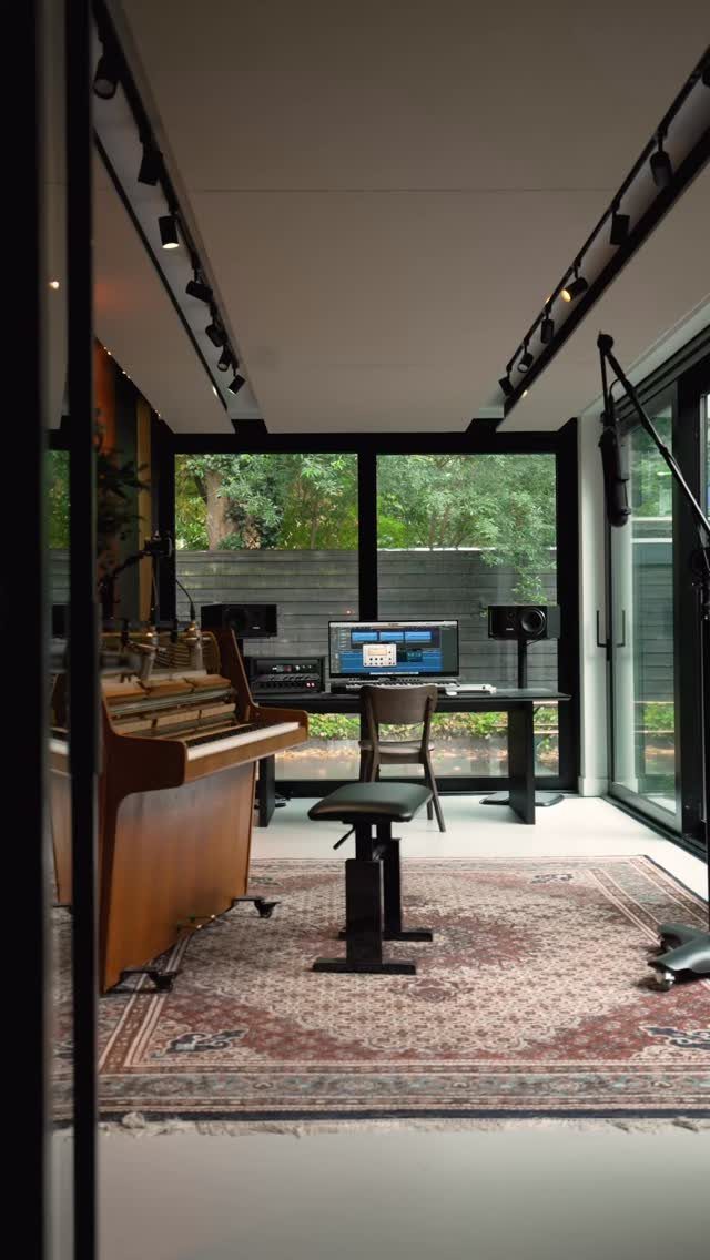 Home music studio with a piano and desk illuminated by bright natural light.