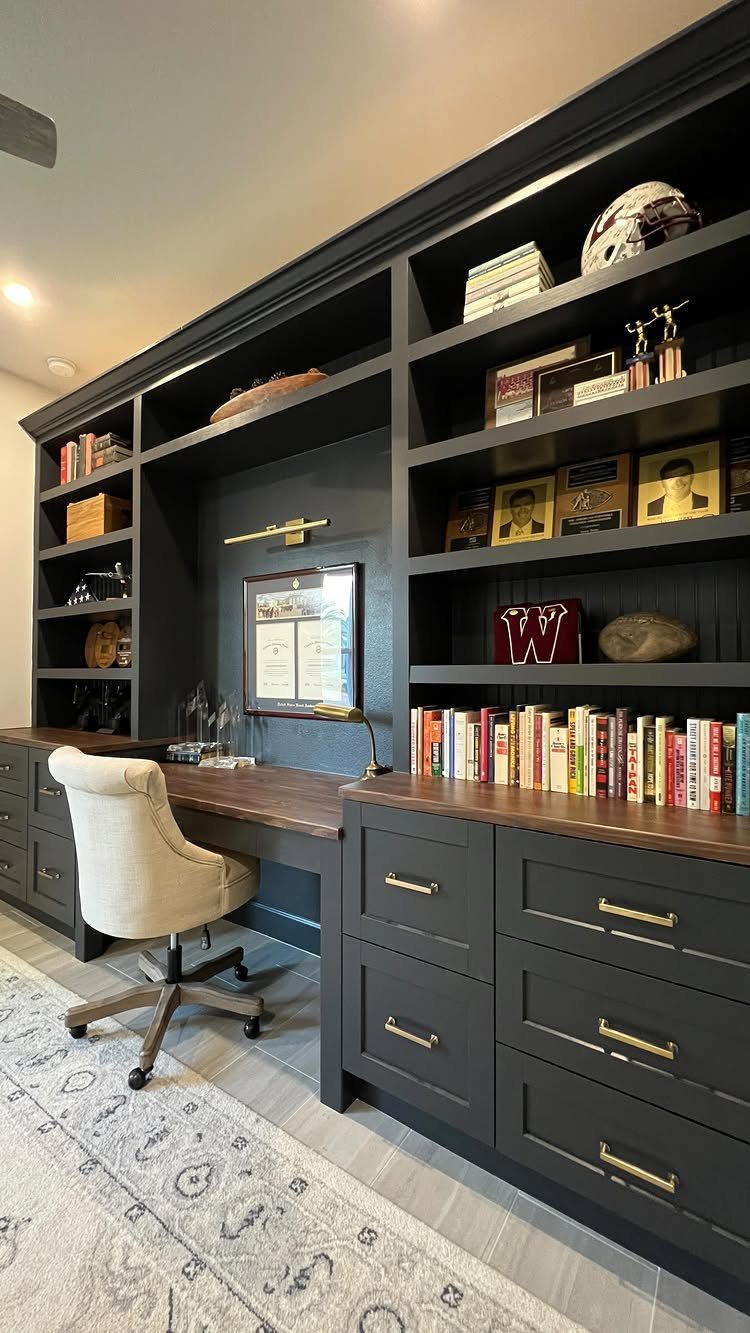 Dark grey built-in office cabinets with wooden desk and open shelving for books.