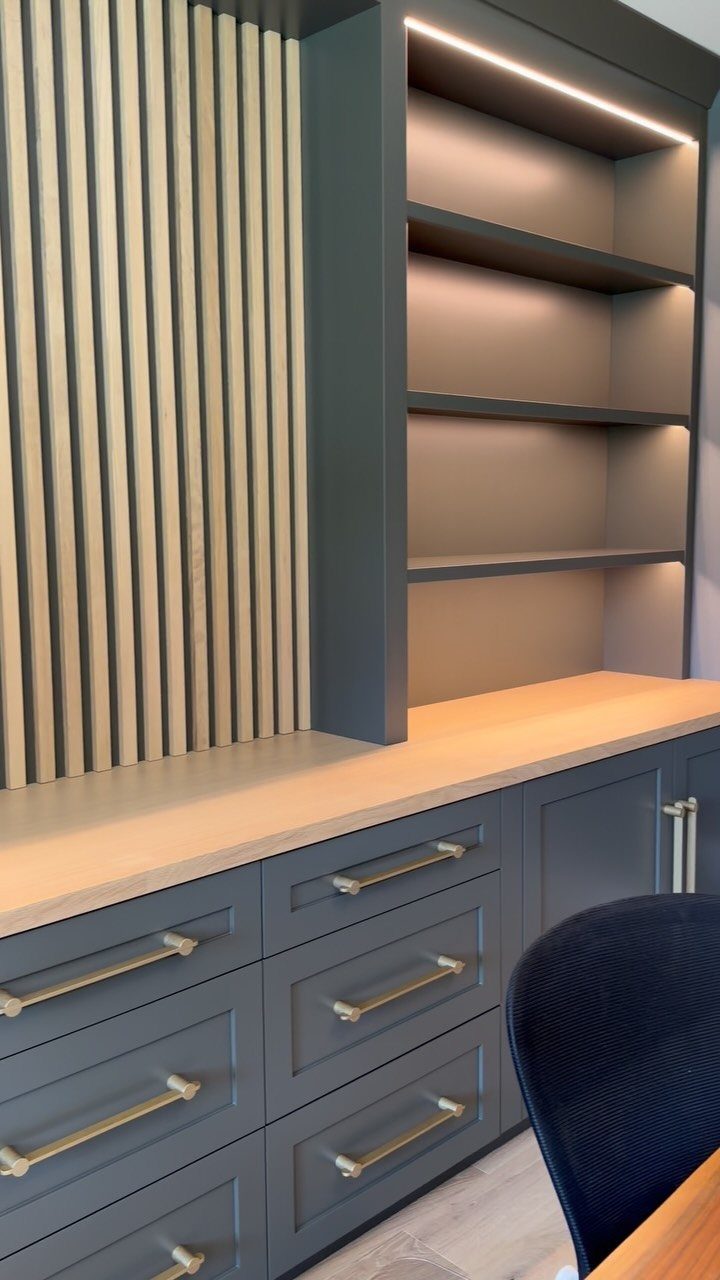 Grey built-in office cabinetry with gold hardware and a wood slat accent wall.