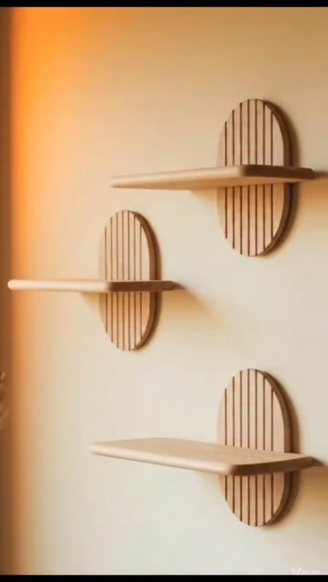 Three light wooden floating shelves with circular slatted backplates on a beige wall.