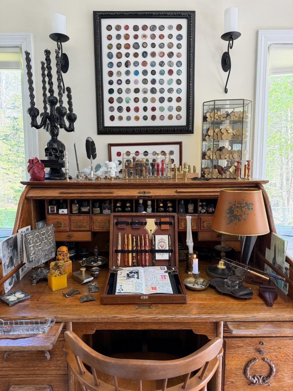 Vintage wooden secretary desk with a framed coin collection and antique office accessories.