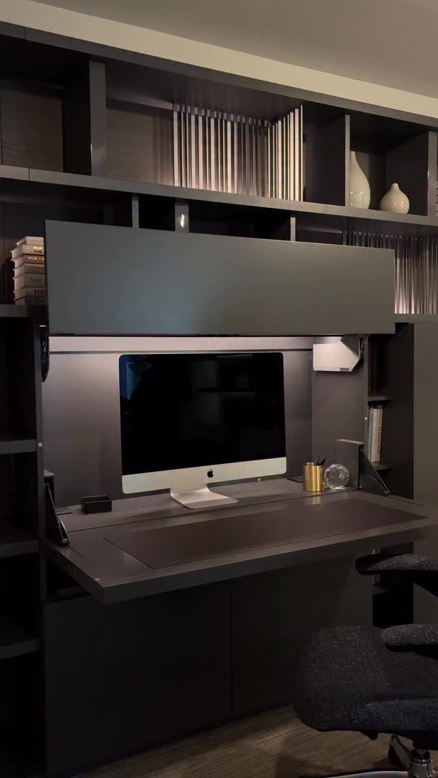 Dark grey built-in home office desk with a computer monitor and overhead shelving.