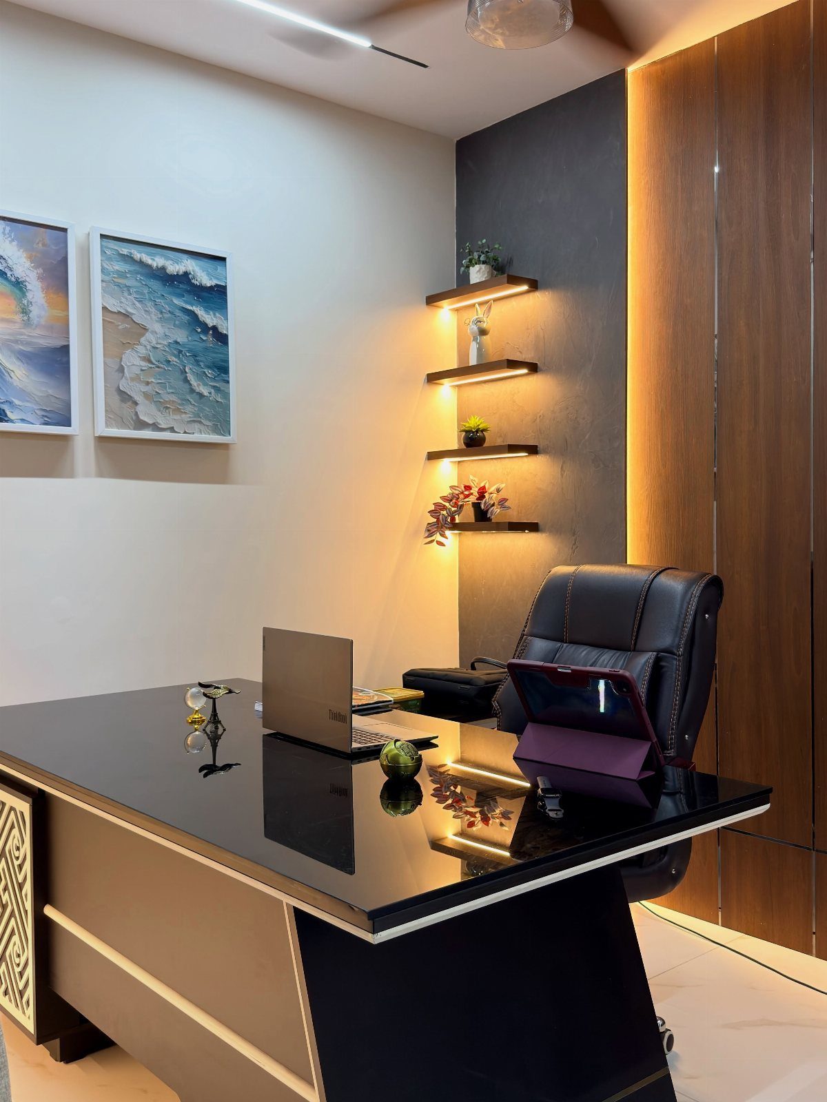 Modern home office with a glossy black desk, leather chair, and illuminated shelves.