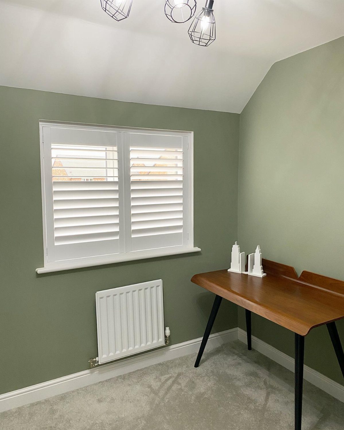 10 Home Office Paint Colors for a Productive Space 8 Sage green office walls with a wooden desk and white window shutters.