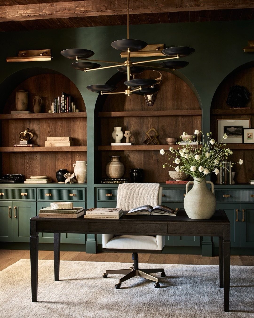 10 Home Office Paint Colors for a Productive Space 2 Dark green home office walls with arched wooden bookshelves and a black desk.