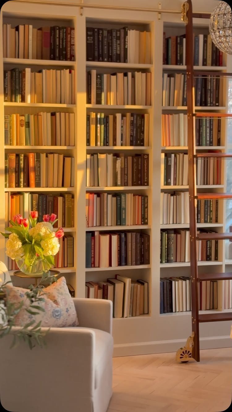 White built-in bookshelves filled with books and a sliding wooden library ladder.