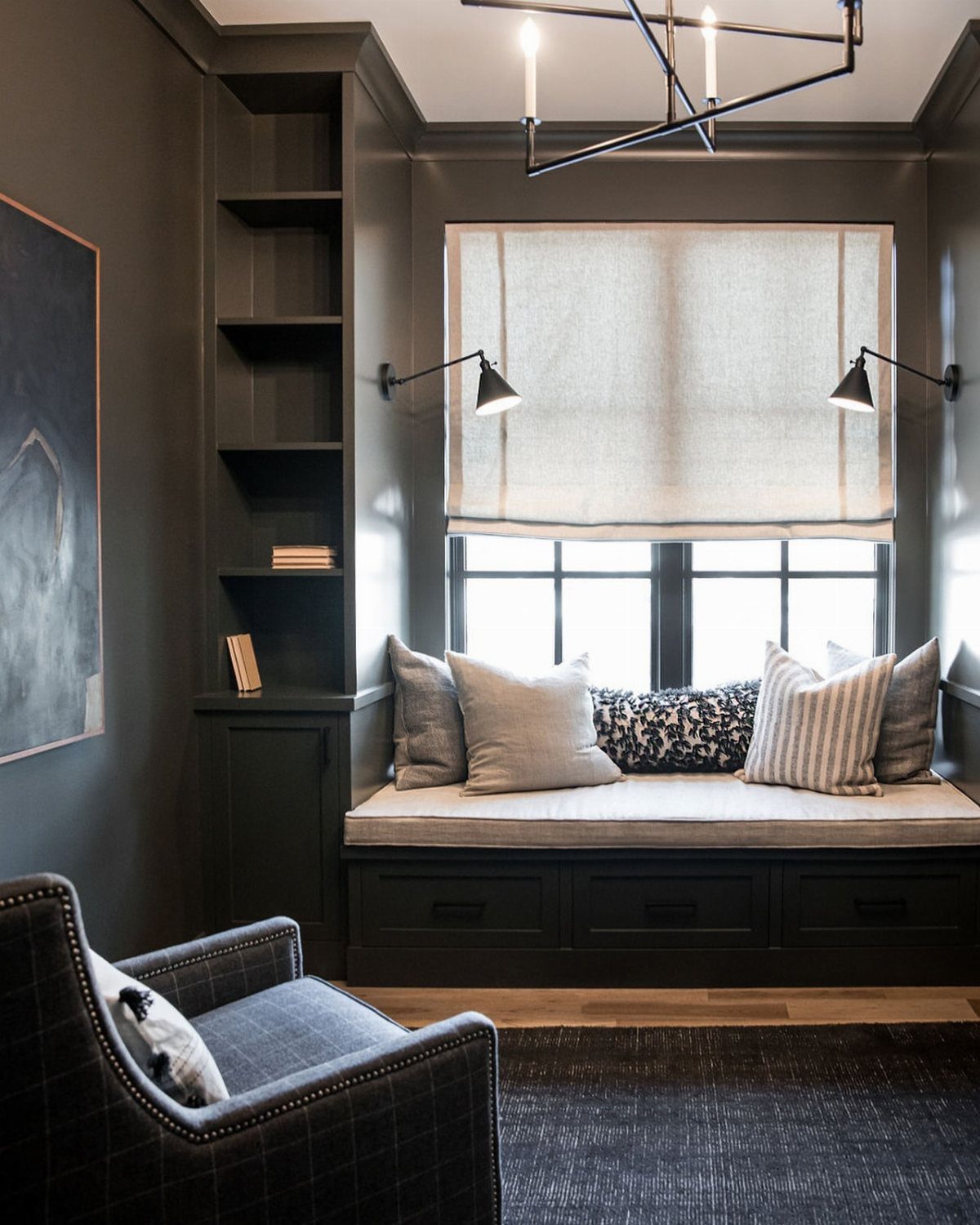 Built-in window seat sofa with grey cushions and pillows in a dark grey office.