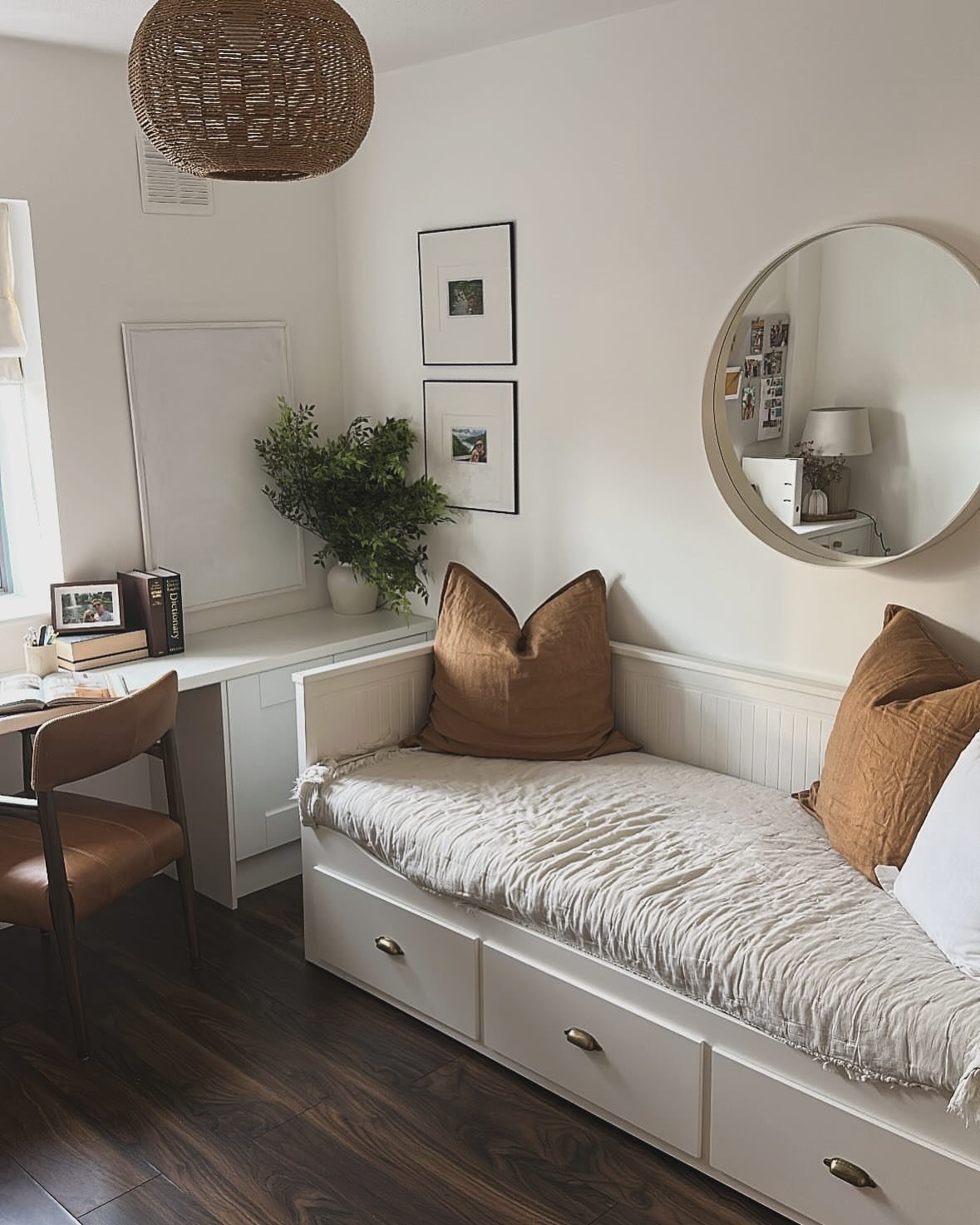 White daybed with storage drawers and brown pillows next to a built-in desk.