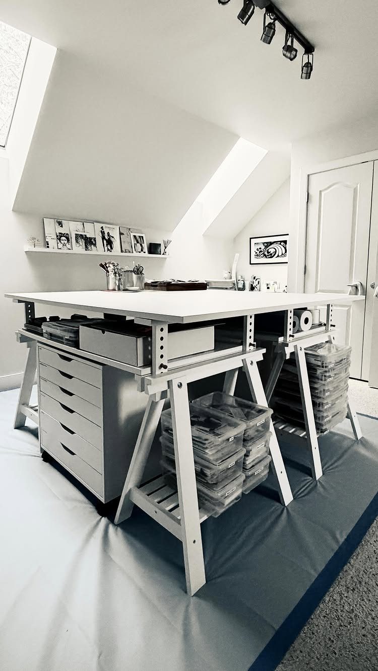 White art studio table with IKEA Alex drawers and trestle legs in bright room.