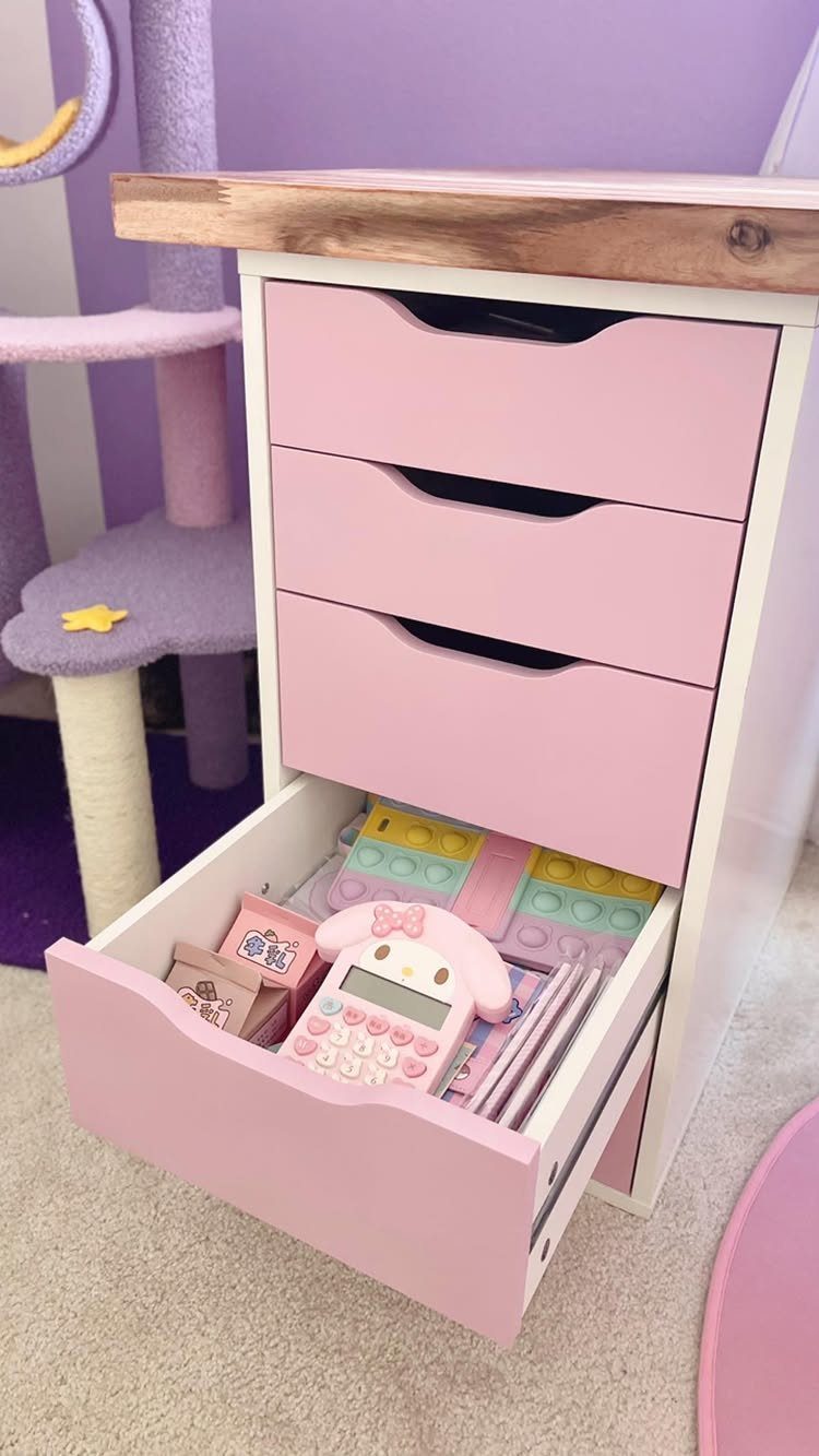 Pink painted IKEA Alex drawer unit with a natural wood desktop and open drawer.