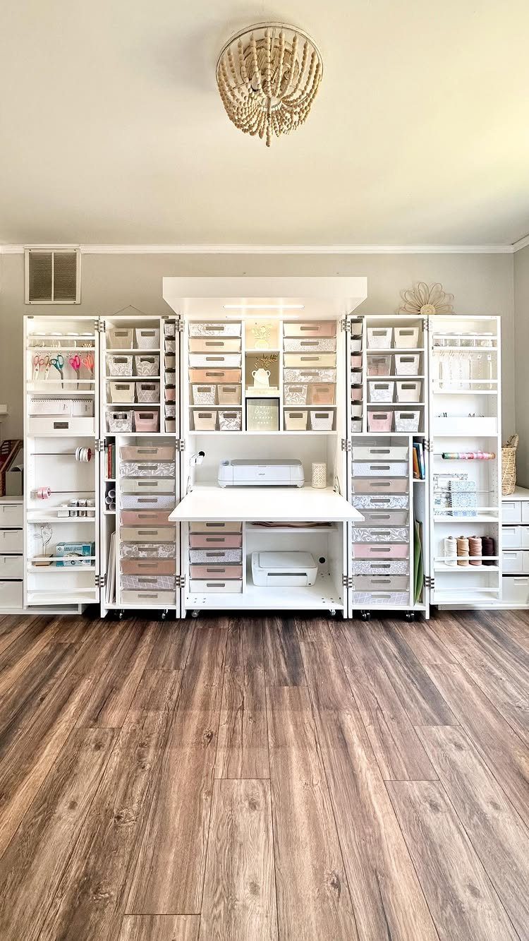 White closet office with built-in desk, organized storage bins, and brown wood flooring.